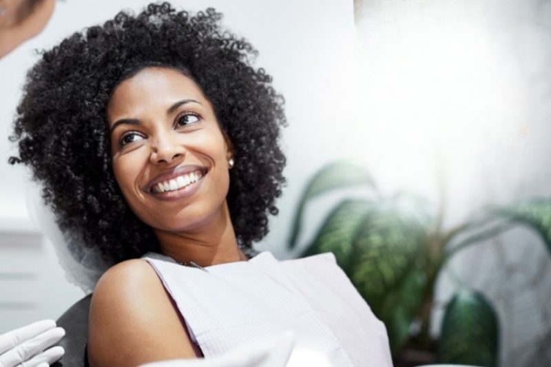 Happy patient in dental chair smiling brightly.